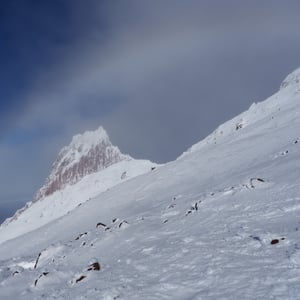 Snowy mountain pinnacle rising through drifting clouds