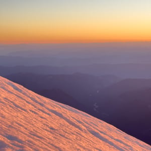 Snow ridge and layered mountains at golden hour