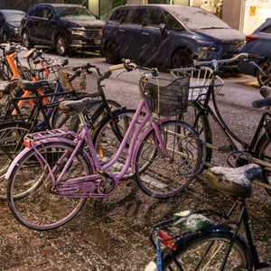 Snowy city bikes parked on cobblestone street at night