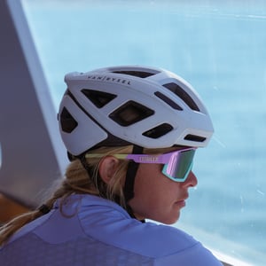 Woman in cycling helmet and sunglasses looking at sea