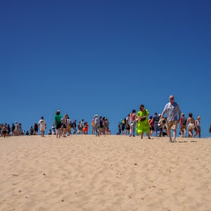 Tourists walking along a sunlit sand dune