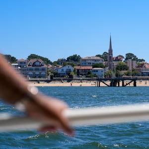 Hand on boat railing overlooking a sunny seaside town