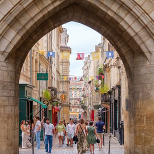 People walking beneath a Gothic stone arch in old town