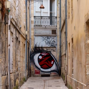 Narrow alley with eye mural and graffiti door