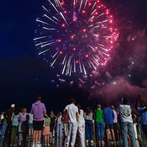 Crowd watching red and white fireworks at night