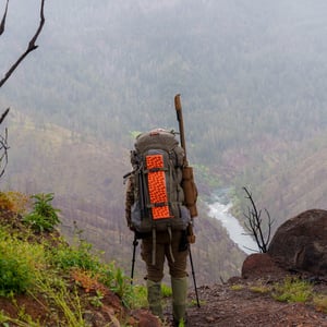 Hiker with backpack overlooking misty canyon and river