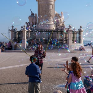 Children catching bubbles beneath an equestrian statue