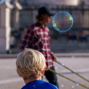 Boy watching soap bubbles float in a sunny square