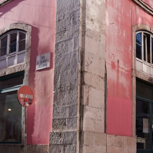 Pink corner building and stone pillar on cobblestone street