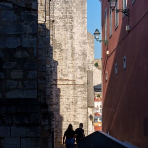 Two people walking up a cobbled alley