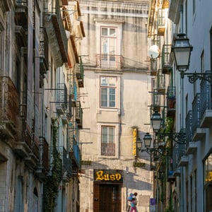 Steep cobblestone street with balconies and fado sign