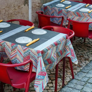 Outdoor café tables with red chairs on cobblestones