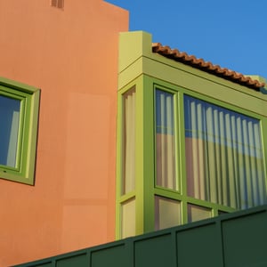 Orange stucco building with green window frames under blue sky