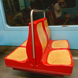 Red subway seats with cork cushions and steel pole