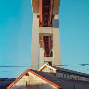 Red steel truss bridge against a bright blue sky
