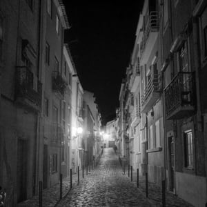 Narrow cobblestone street at night in black and white