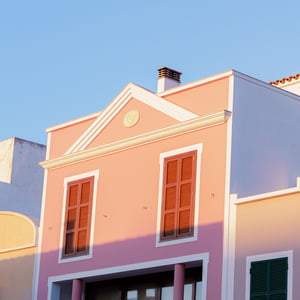 Pastel Mediterranean building facade with brown and green shutters