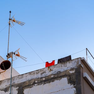 Rooftop antennas and laundry against a blue sky