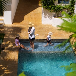 Family cooling off in a sunny courtyard pool