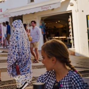 Tourists walking past a whitewashed shop on sunny steps