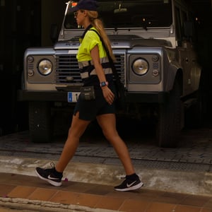 Woman in neon yellow shirt walking past a Land Rover