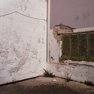 Weathered corner with peeling walls and green shutter