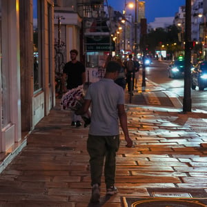 Man carrying roses on wet cobblestone street at dusk