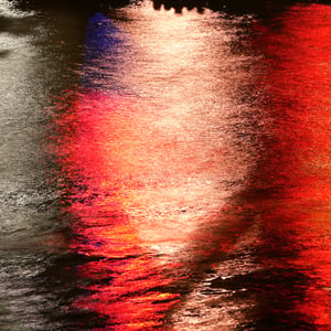 Red and white city lights reflected on rippling water