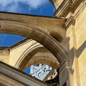 Layered stone arches framing a spire against blue sky