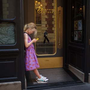 Girl checking yellow phone in Paris doorway