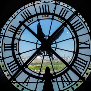 Woman silhouetted by Musée d'Orsay clock window over Paris