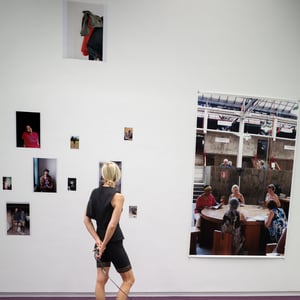 Woman walking grey dog past gallery photo wall