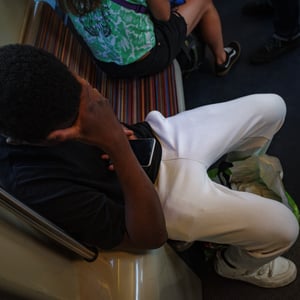 Young boy resting head on hand on striped train seat