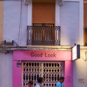 Pedestrians walking past a pink eyelash studio